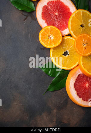 Different sliced citrus on dark concrete background Stock Photo