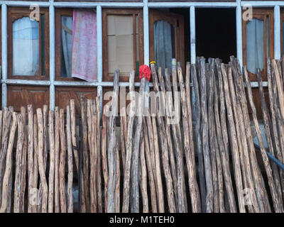 Wall of the house, on top of a row of wooden old windows, from below huge wooden beams, leaning against the wall, a modern background of the interior  Stock Photo