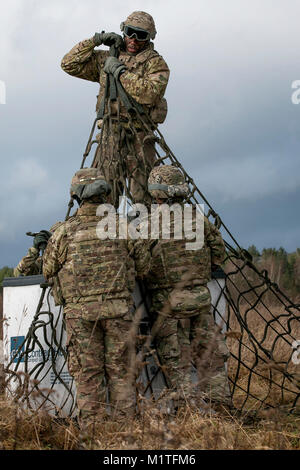 Spc. Antonio Ross (top, center), an automated logistics specialist assigned to the 299th Brigade Support Battalion, 2nd Brigade Combat Team, 1st Infantry Division, Fort Riley, Kansas, prepares equipment to be sling loaded from a helicopter at Skwierzyna, Poland on Jan. 4, 2017. Sling loading is a method of rapidly transporting equipment that is tethered to the bottom of a helicopter with a rope. (U.S. Army Stock Photo