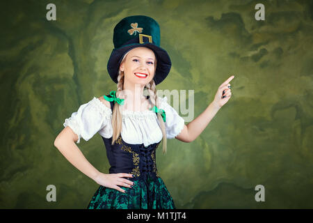 A girl dressed as St. Patrick points with her finger against a g Stock Photo