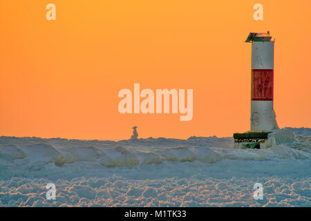 ice cairn on frozen winter pier with red and white striped beacon Stock Photo