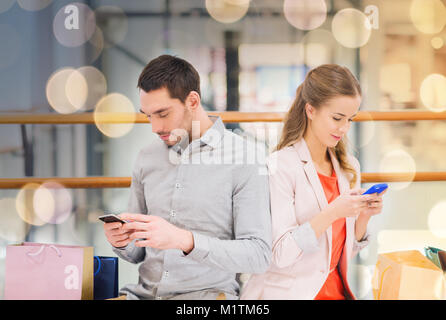 couple with smartphones and shopping bags in mall Stock Photo