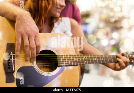 close up of couple playing guitar over lights Stock Photo
