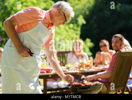 senior man cooking meat on barbecue grill outdoors Stock Photo