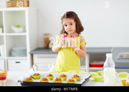 little girl in chefs toque baking muffins at home Stock Photo