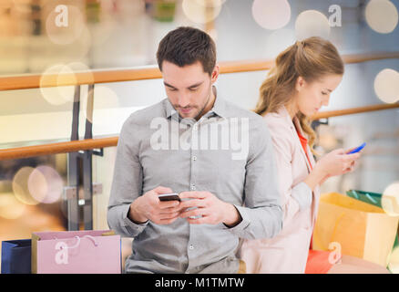 couple with smartphones and shopping bags in mall Stock Photo