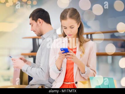 couple with smartphones and shopping bags in mall Stock Photo