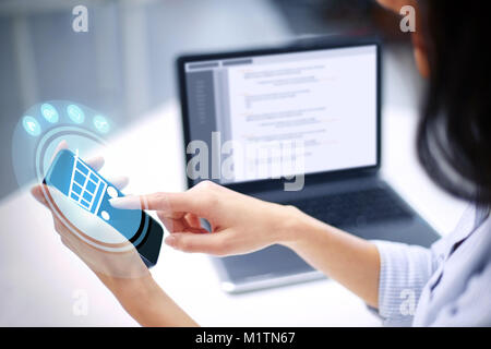close up of woman with shopping cart on smartphone Stock Photo