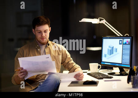 designer with papers working at night office Stock Photo
