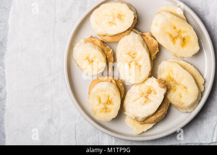 Light Healthy Snack made from Banana Slices and Cashew Butter, on Grey Background Stock Photo