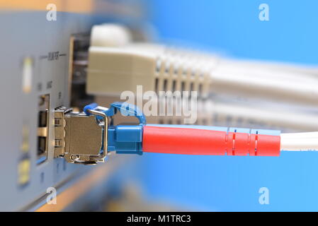 Optical fiber patch cord and network cables connected to switch in datacenter, closeup Stock Photo