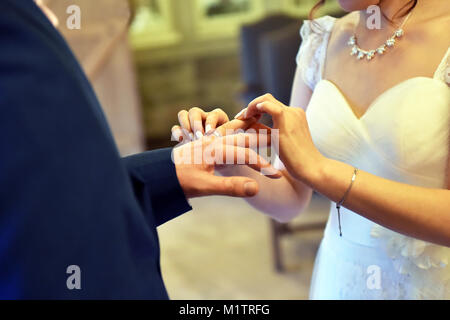Wedding couple exchange rings on their wedding day, close up of placing ring on finger. Stock Photo