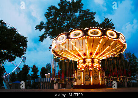 Children's beautiful amusement in entertainment park in the blue hour enabled illumination yellow color against the blue sky Stock Photo