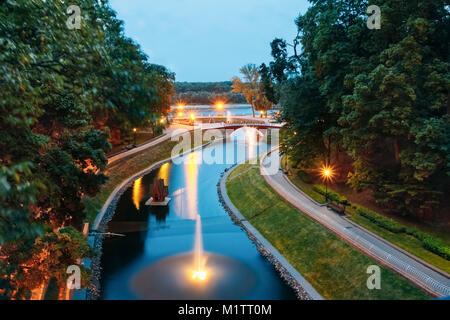 Water canal in the city park with the lights and night illumination over a stone bridge leading to the river Sozh Stock Photo