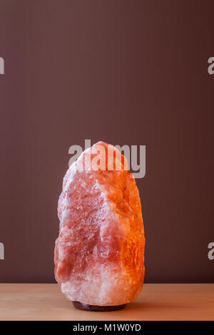 Himalayan salt lamp on wooden table - not illuminated Stock Photo