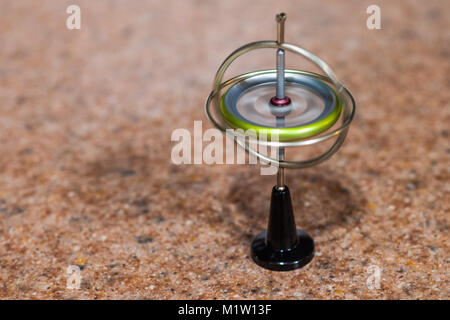 Toy gyroscope spinning and balancing on a small stand Stock Photo