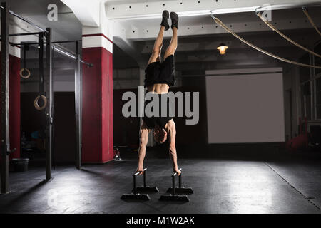 Young Athlete Man Doing Handstand Exercise On Parallel Bar In The Gym Stock Photo