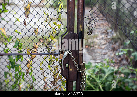 Rusty fence locked with padlock and chain protecting an abandoned property Stock Photo