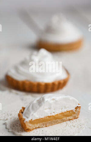 lemon tartlets with white air cream against on wooden table. Stock Photo