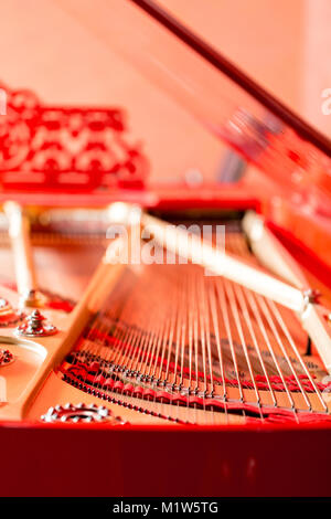 Strings close-up. Vintage red classical grand piano. Musical instrument abstract. Stock Photo