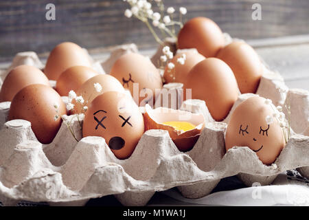 Eggs with funny faces standing in egg box Stock Photo