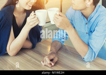 Happy young couple people relaxing meeting and drinking tea or coffee in cafe. Looking happy dating. Stock Photo