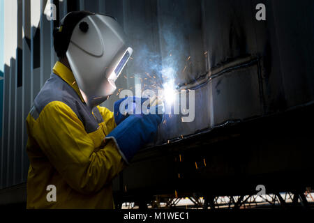 Industry worker with welding steel to repair container structures manufacture workshop. Container maintenance industry. Stock Photo