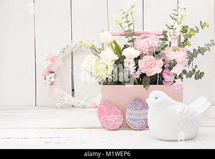 Happy Easter decoration for greeting card. Wooden bird, gingerbread Easter cookies in shape of Easter eggs and basket with flowers on white background Stock Photo