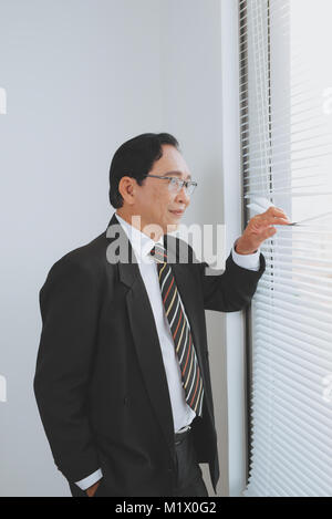 Mature boss contemplating in his office, thinking and looking through window. Stock Photo