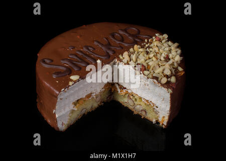 A piece of chocolate cake with hazelnut with white cream on a black background Stock Photo