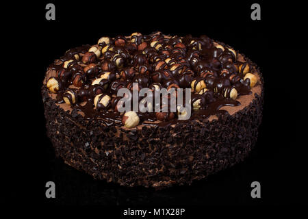Chocolate cake with hazelnuts with white cream on a black background closeup Stock Photo