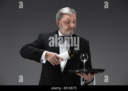 professional waiter in uniform is serving wine Stock Photo