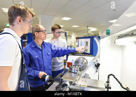 young apprentices in technical vocational training are taught by older trainers on a cnc lathes machine Stock Photo