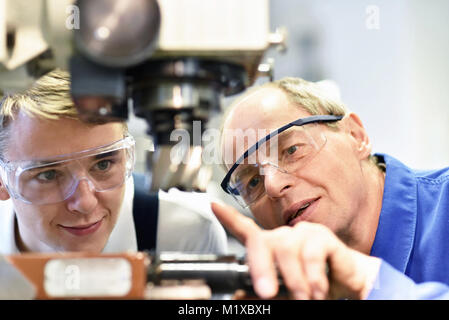 closeup picture: trainer and apprentice in vocational training on a milling machine - teacher explains details of the machine Stock Photo