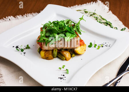 Baked fish fillets with potatoes and green beans on a square plate Stock Photo