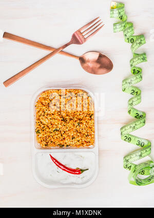 Healthy diet lunch eating  with couscous salad and yogurt. Vegetarian salad lunch box in plastic package with cutlery and Measuring tape on withe wood Stock Photo