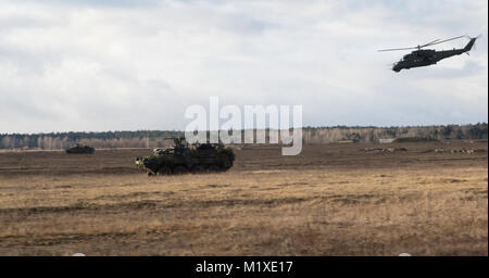 U.S. Soldiers from Kronos Troop, 3rd Squadron, 2nd Cavalry Regiment, drive their Strykers to their battle positions while a Polish MI-24 helicopter provides aerial support as they participate in a NATO live fire exercise coordinated by the Polish 1st Battalion 15th Mechanized Brigade at a range near the Bemowo Piskie Training Area, Poland, Jan. 30, 2018. The unique, multinational battle group, comprised of U.S., U.K., Croatian and Romanian soldiers serve with the Polish 15th Mechanized Brigade as a deterrence force in northeast Poland in support of NATO’s Enhanced Forward Presence. (U.S. Army Stock Photo