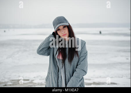Stylish brunette girl in gray cap, casual street style on winter day. Stock Photo
