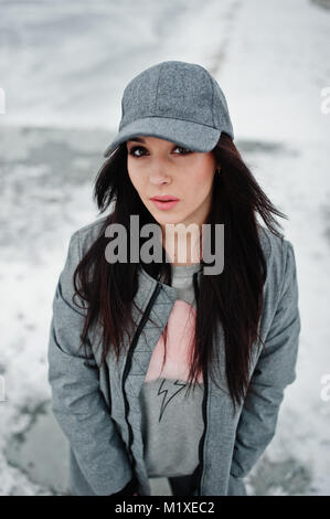 Stylish brunette girl in gray cap, casual street style on winter day. Stock Photo