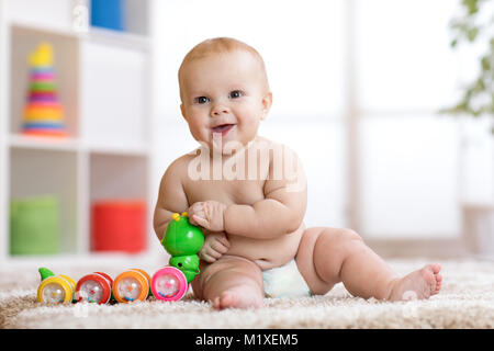 Cute little baby boy 8 months old sits and plays with toys in nursery room Stock Photo