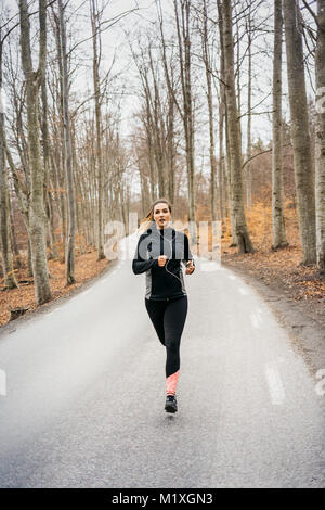 Young woman running on rural road in Sodermanland, Sweden