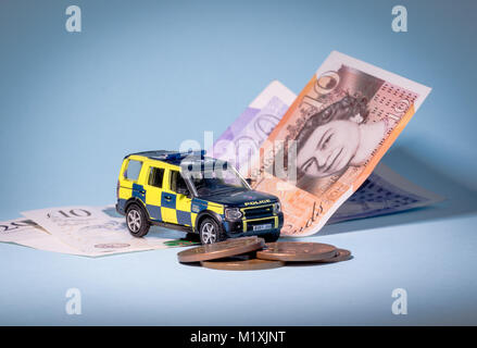 Miniature Police vehicle on cash notes and coins Stock Photo