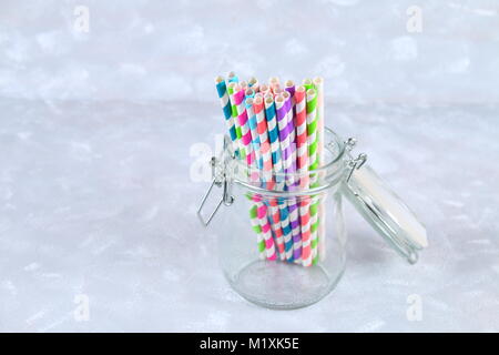 colorful striped paper disposable tubes in a jar on a gray background Stock Photo