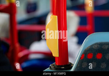 A public transport yellow and red press button on a hand rail inside the Dundee Xplore Hybrid bus in Dundee, UK Stock Photo