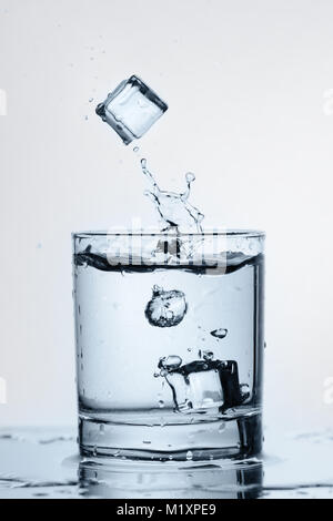 Ice cubes are dropping in to the glass of pure water. Stock Photo