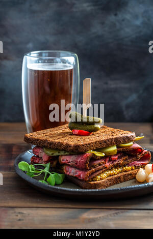 Delicious huge pastrami sandwich with beer and pickle Stock Photo