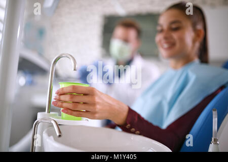 Close up of woman’s hand taking glass of water in dental chair Stock Photo