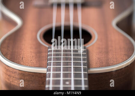 Tenor ukulele close-up of frets and strings on fretboard near ukulele body Stock Photo