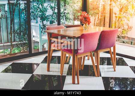 Vintage colorful wooden table and chair on checkered pattern floor in the restaurant with sunlight radiate from top left corner. Stock Photo