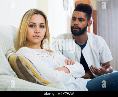 Young interracial family couple with serious faces arguing at home Stock Photo